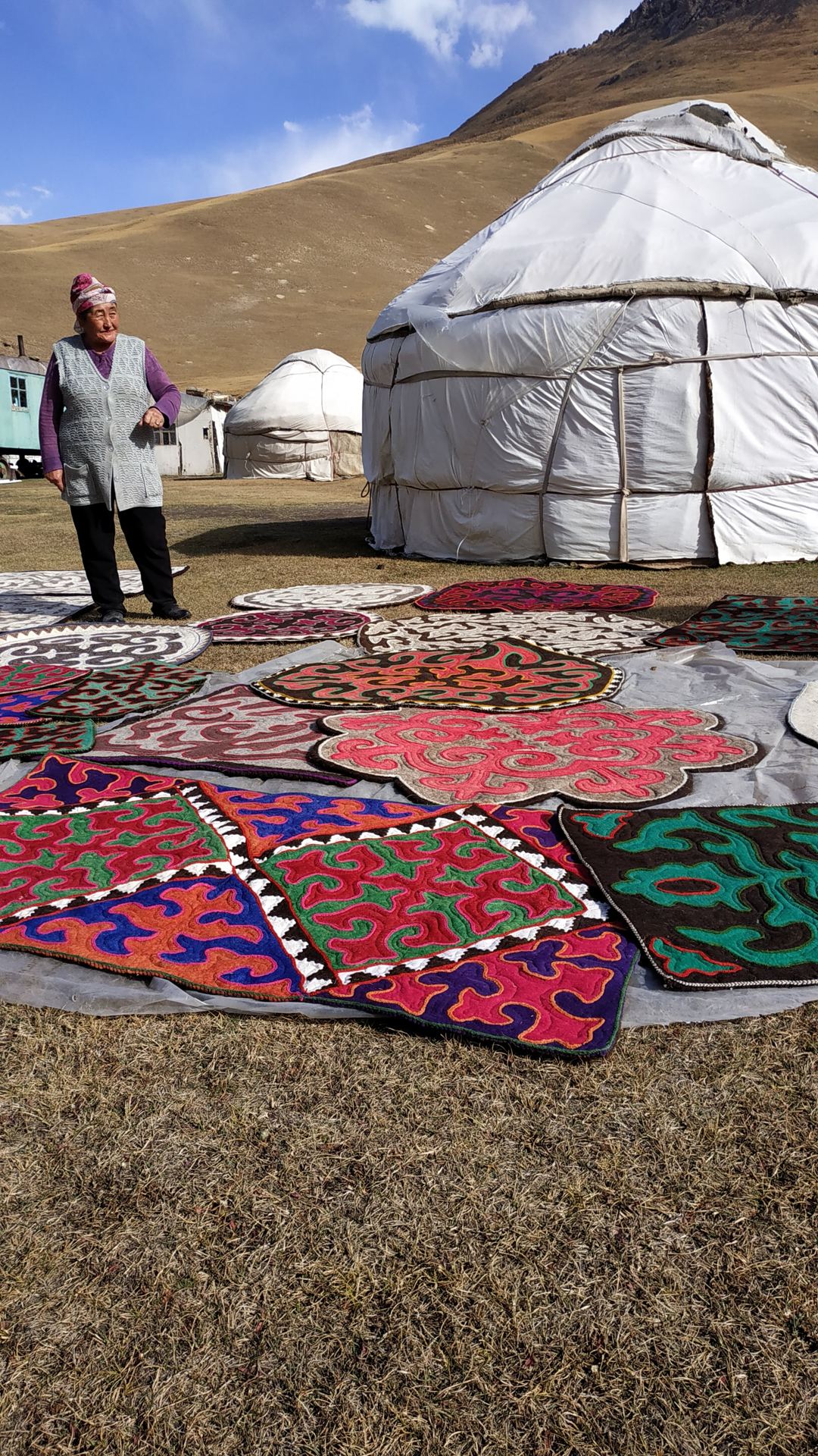White yurt with colourful felt carpets laid out on the grass (partner-supplied Kyrgyzstan photo)